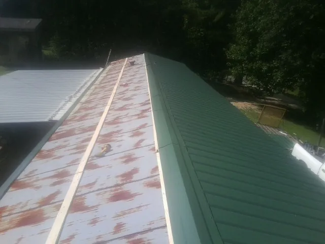 Old rusted panels beside newly installed green metal roofing — Wind Damage Roof Repair by Roofing Brothers in Bridgeville