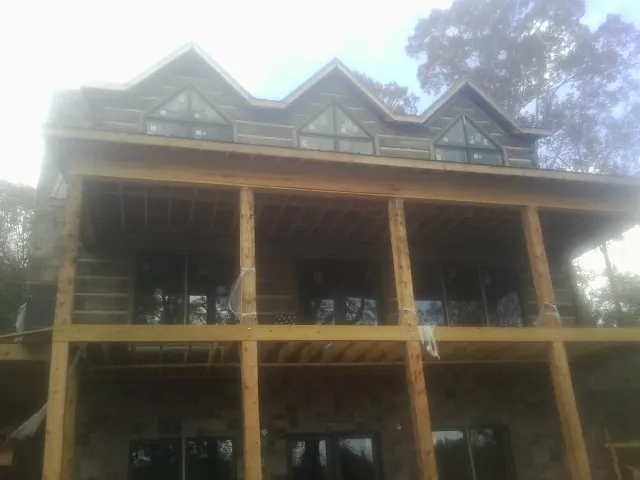 Dormers and porch framing on a large log home under construction — Roof Coating work by our crew in Bridgeville